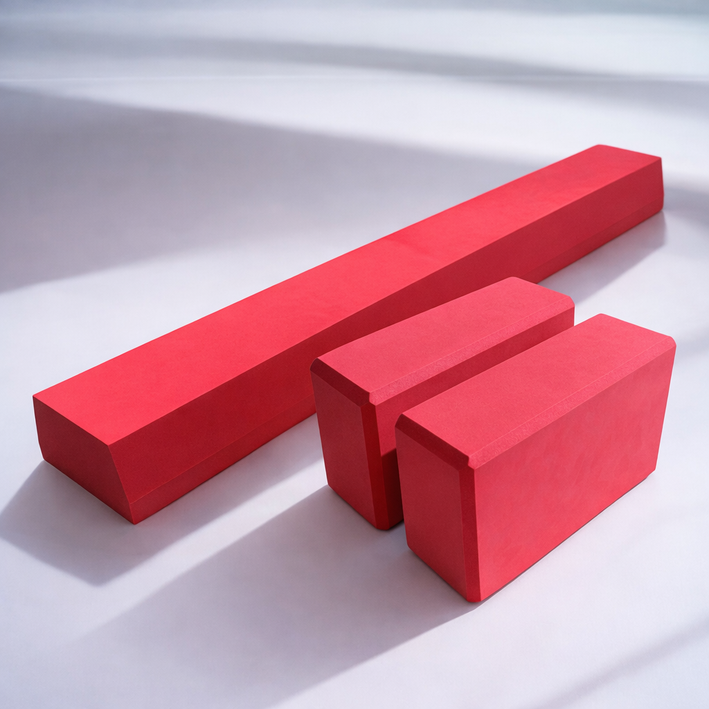 Roter Balance Balken aus Schaumstoff zusammen mit 2 passenden Yogablöcken für Yoga, Balance-Übungen und Rehabilitation, auf weißem Untergrund.